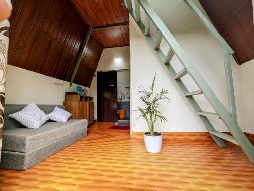 a living room with a couch and a staircase at Coorgology - The estate stay in Madikeri