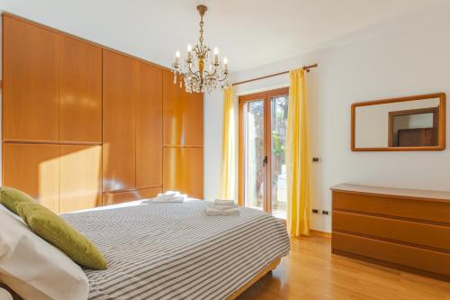 a bedroom with a bed and a chandelier at Appartamento in villa con terrazza vista mare - pet friendly in Trieste