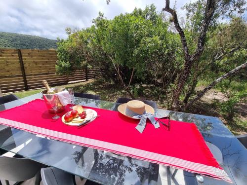 a red table with a hat and a plate of food at Alkantmooi Private Nature Reserve - Keurkloof & Keurbos 93 in Plettenberg Bay