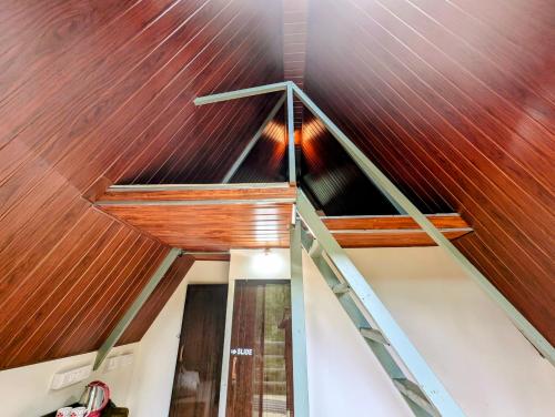 an attic with a wooden ceiling and a staircase at Coorgology - The estate stay in Madikeri