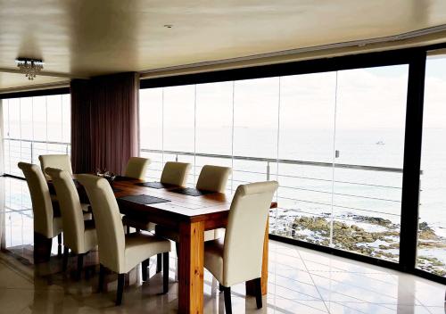 a dining room table with chairs and a large window at Crystal Lagoon Lodge in Langebaan