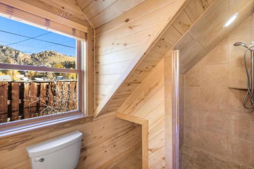 Un baño de madera con inodoro y ventana. en The Coach House, en Creede