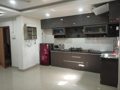 a kitchen with brown cabinets and a red refrigerator at Luxury Bonafide Villa in Lohārghāt