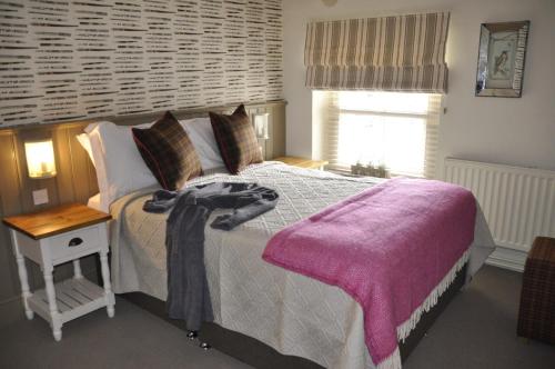 a bedroom with a bed with a purple blanket on it at Higher Buck Inn in Waddington