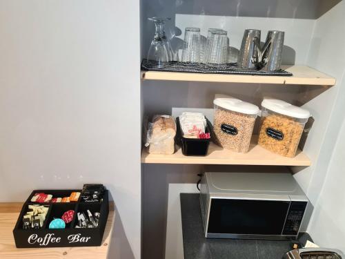 a kitchen with a shelf with cups and a microwave at Peebles High Street Apartment in Peebles
