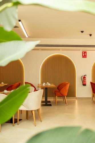a restaurant with orange chairs and a table at Hotel El Tujjar in Los Barrios