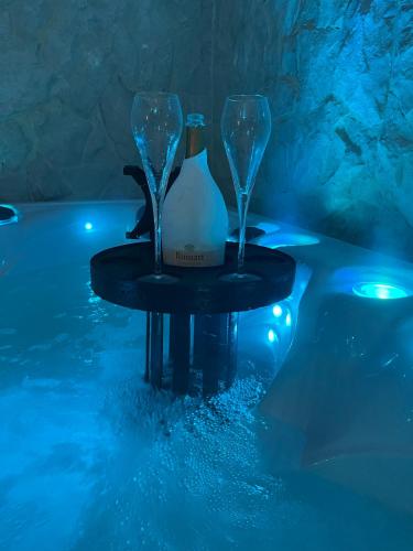 - deux verres à vin et une bouteille sur une table au bord de la piscine dans l'établissement Rêves de pampa Casa Bohème, à Lorgues