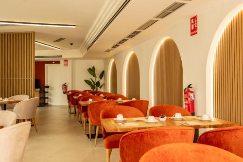 a dining room with tables and chairs in a room with arches at Hotel El Tujjar in Los Barrios