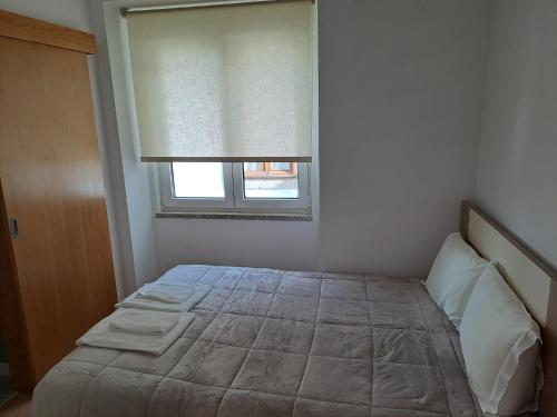 a bedroom with a large bed with a window at Casa da Travessa in Seia