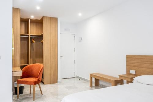 a bedroom with a bed and a desk and a chair at Hotel El Tujjar in Los Barrios