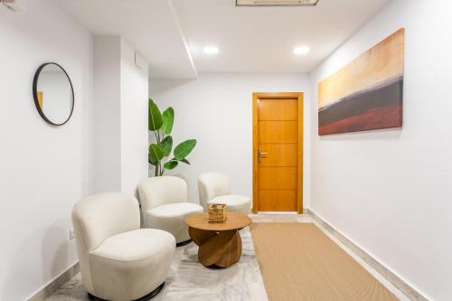 a living room with white chairs and a table at Hotel El Tujjar in Los Barrios