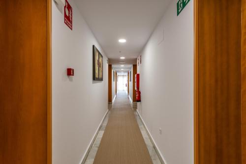 a long hallway with white walls and a long hallway at Hotel El Tujjar in Los Barrios