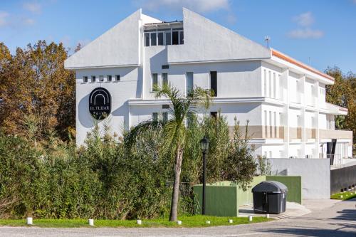 a white house with a palm tree in front of it at Hotel El Tujjar in Los Barrios