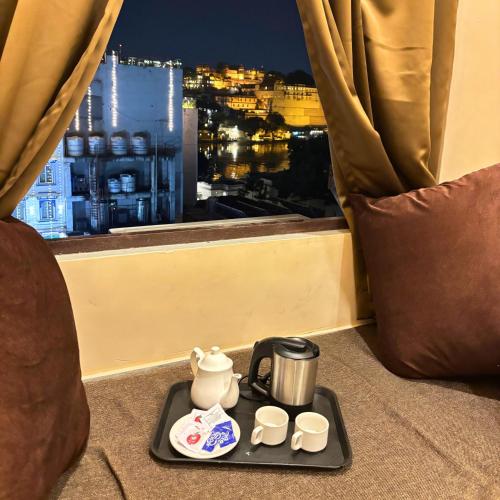 a tray with a tea kettle and cups on a balcony at Hotel Nirvana Lakeside in Udaipur