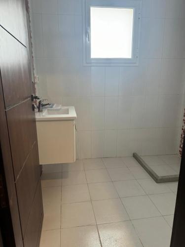 a white bathroom with a sink and a window at La patine des portes in Sfax