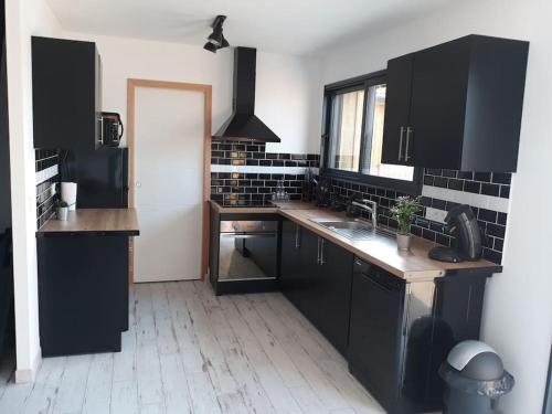 d'une cuisine avec des placards noirs, un évier et une fenêtre. dans l'établissement AIMI-AQUO gîte, Bassin d'Arcachon Sud, à Gujan-Mestras