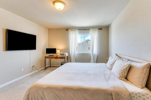 a bedroom with a large bed with a flat screen tv at 10 Mi to Fort Carson Newly Built Townhome! in Fountain