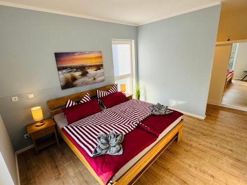 a bedroom with a large bed with red and white sheets at 8 Personen Ferienhaus ,,Seegelblick" am Goitzschesee, erste Reihe am Strand mit Sauna, Kamin, Wallbox & SUP in Pouch