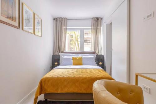 a bedroom with a bed with a yellow blanket and a chair at Bright Urban Cukor Suite - Balcony - Free Parking - Near Arena & Jarun in Zagreb