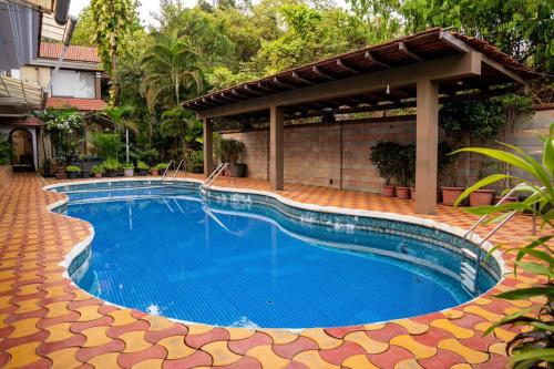 a large swimming pool with a pavilion next to a house at Calangute Candolim Beach Bay villas and Apartments in Baga