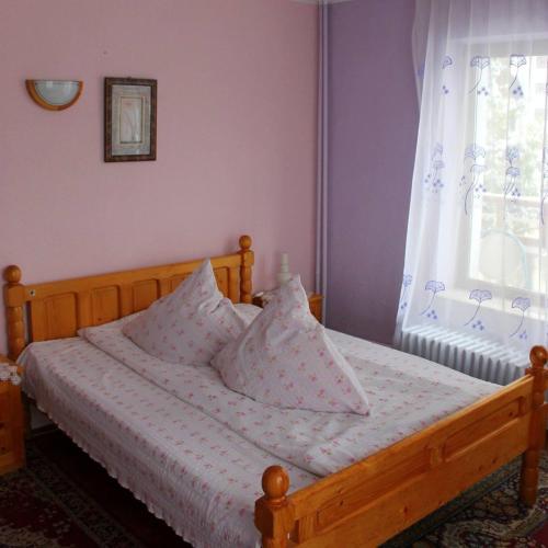 a bedroom with a wooden bed with pillows and a window at Vila cu vedere spre Bucegi in Predeal