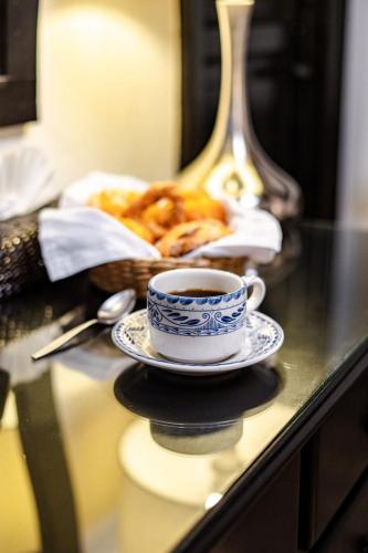 a cup of coffee on a table with a basket of pastries at Best Western Plus Posada de Don Vasco in Pátzcuaro