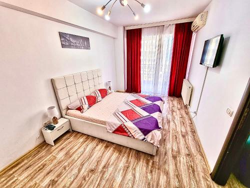 a bedroom with a bed and a window with red curtains at Summerland Seaview Apartments in Mamaia