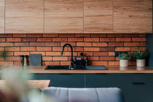 a kitchen with a sink and a brick wall at Balans nad Jeziorem in Ślesin