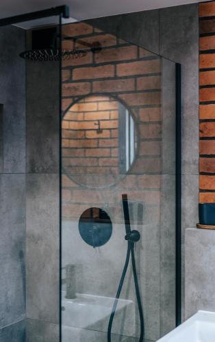 a glass shower in a bathroom with a brick wall at Balans nad Jeziorem in Ślesin