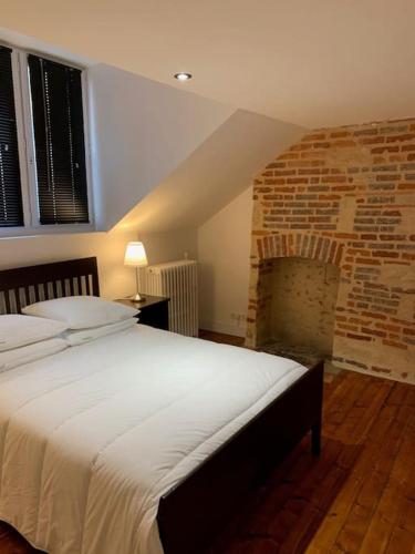 - une chambre avec un grand lit et une cheminée en briques dans l'établissement Appartement #4 cœur de ville, au Mans