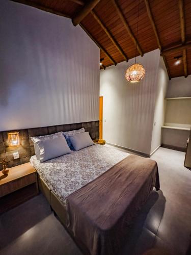 a bedroom with a large bed and a chandelier at Vila Tanrral in Lençóis