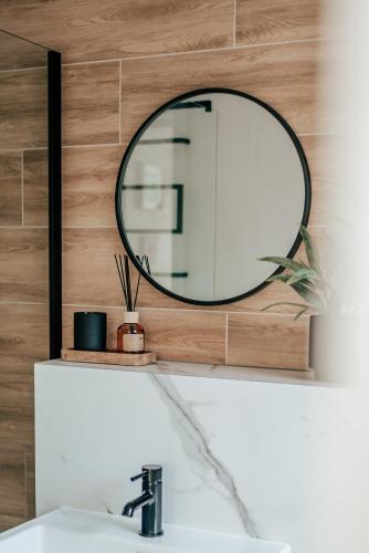 a mirror on a wooden wall above a sink at Balans nad Jeziorem in Ślesin