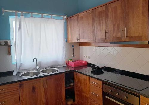 a kitchen with wooden cabinets and a sink and a window at Villa Lagosta Stella Maris Exclusive in Vila do Maio