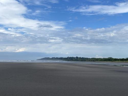 an empty beach with a blue sky and clouds at Esterillos Lote home in Esterillos