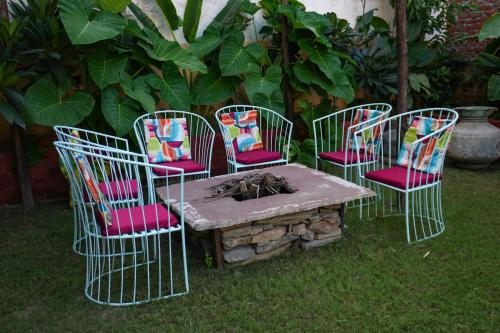 a group of four chairs and a table in the grass at PETAL OF MEWAR - A Luxury Boutique Hotel in Udaipur