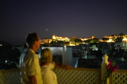 a group of people sitting on a roof looking at the city at PETAL OF MEWAR - A Luxury Boutique Hotel in Udaipur