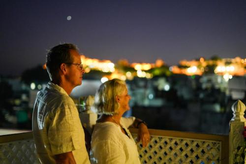 a man and woman standing on a balcony looking at the city at PETAL OF MEWAR - A Luxury Boutique Hotel in Udaipur
