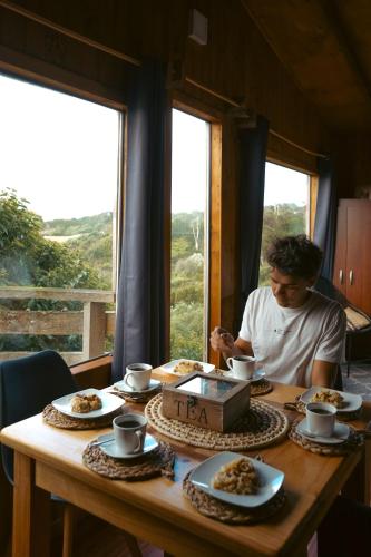 a man sitting at a table with plates of food at Pumillahue Lodge cabaña matrimonial in Ancud