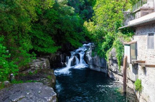 a waterfall next to a river with buildings and trees at Charming Studio with Shared Pool in Loro Ciuffenna in Loro Ciuffenna