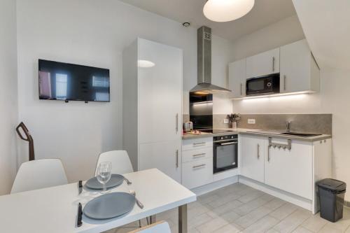 une cuisine avec des armoires blanches et une table et des chaises dans l'établissement Hervé maison de ville, à Rouen