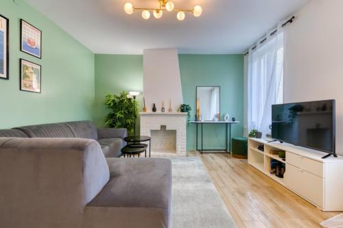 un salon avec un canapé et une télévision dans l'établissement Trixie jolie maison avec jardin, à Rouen