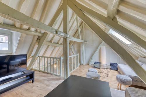 - un salon mansardé avec une table et une télévision dans l'établissement Damiette charmant F4 centre Rouen St Maclou !, à Rouen
