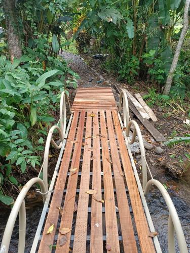 a wooden bench sitting next to a walkway at Bamboo River Lodge in Horquetas