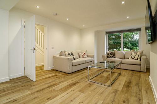 a living room with two couches and a glass table at Wyndford Riverside House in Glasgow