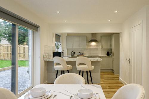 a kitchen and dining room with white chairs and a table at Wyndford Riverside House in Glasgow