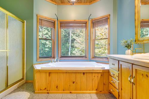 a bathroom with a large tub and two windows at Private Deck and Fire Pit Adirondack Family Home in Old Forge