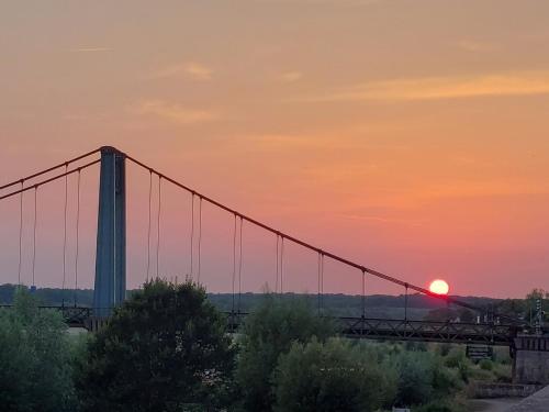 a bridge with the sunset in the background at Logis Loire Hotel - Les Cocottes Restaurant in Les Rosiers-sur-Loire