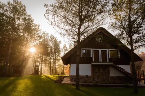 a house in the middle of a yard with the sun shining at LEŚNA STRZECHA APARTAMENTY in Rotembark