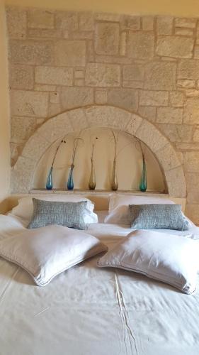 a white bed with four pillows in front of a stone wall at Private Villa with Panoramic View in Ayía Evthimía