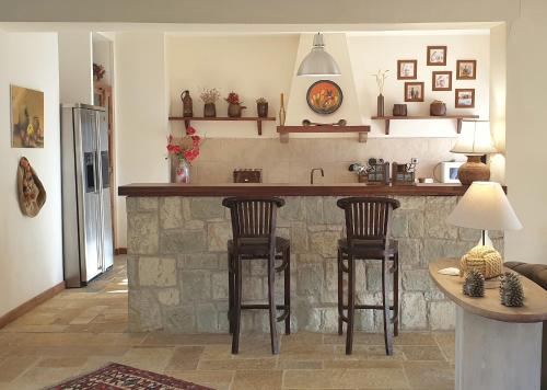 a kitchen with a bar with two stools at Private Villa with Panoramic View in Ayía Evthimía